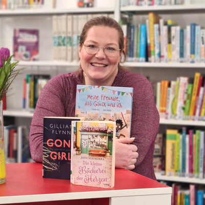 Bibliothekarin Julia Donathh steht an einem Tisch mit B&uuml;chern in der Bibliothek.