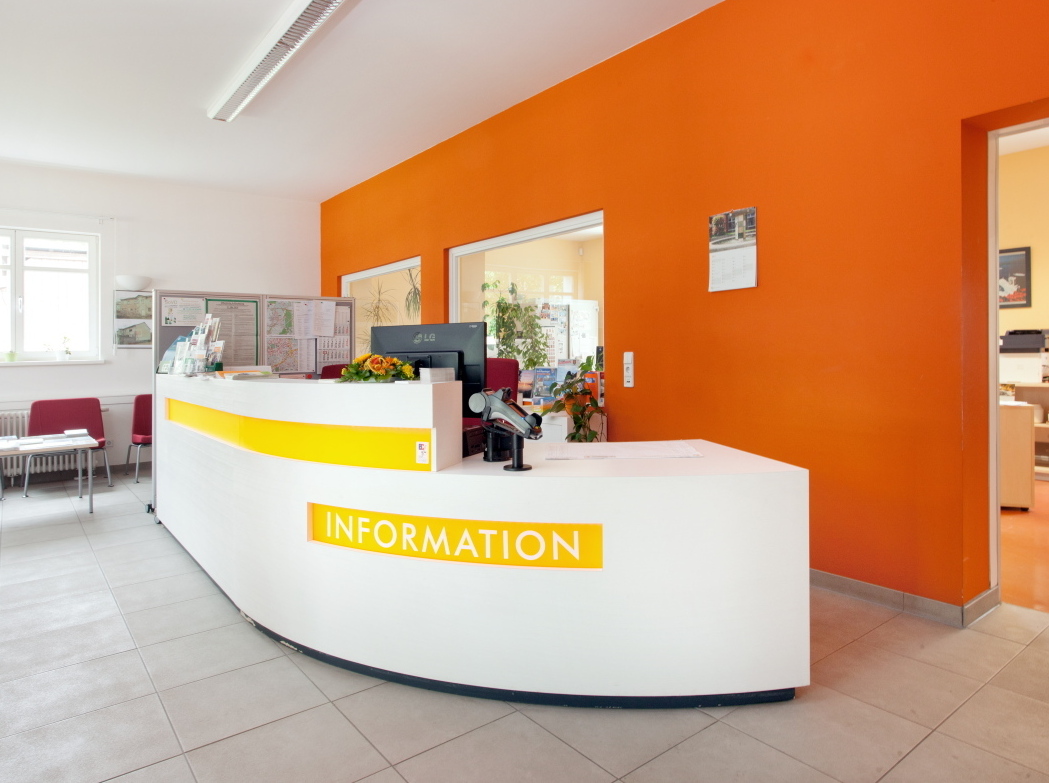 Bild vergrößern: Am weißen Thresen mit gelber Aufschrift "information" beraten die Mitarbeiterinnen und Mitarbeiter des Bürgerservice Velten.