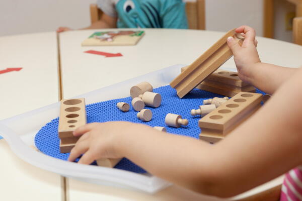 Bild vergrößern: Kinderhände bauen mit Holzbausteinen.