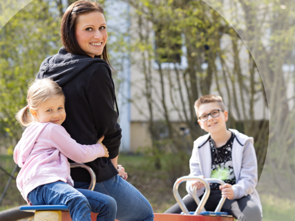 Bild vergrößern: Eine Mutter sitzt mit beiden Kindern auf Wippe.