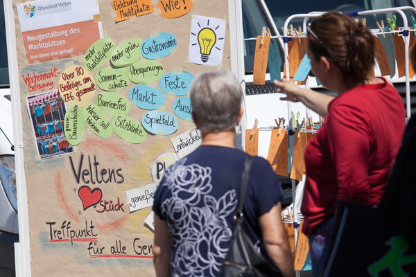 Bild vergrößern: Bürger stehen vor einer bunten Wand und wirken mit Ideen bei der Innenstadtgestaltung mit.