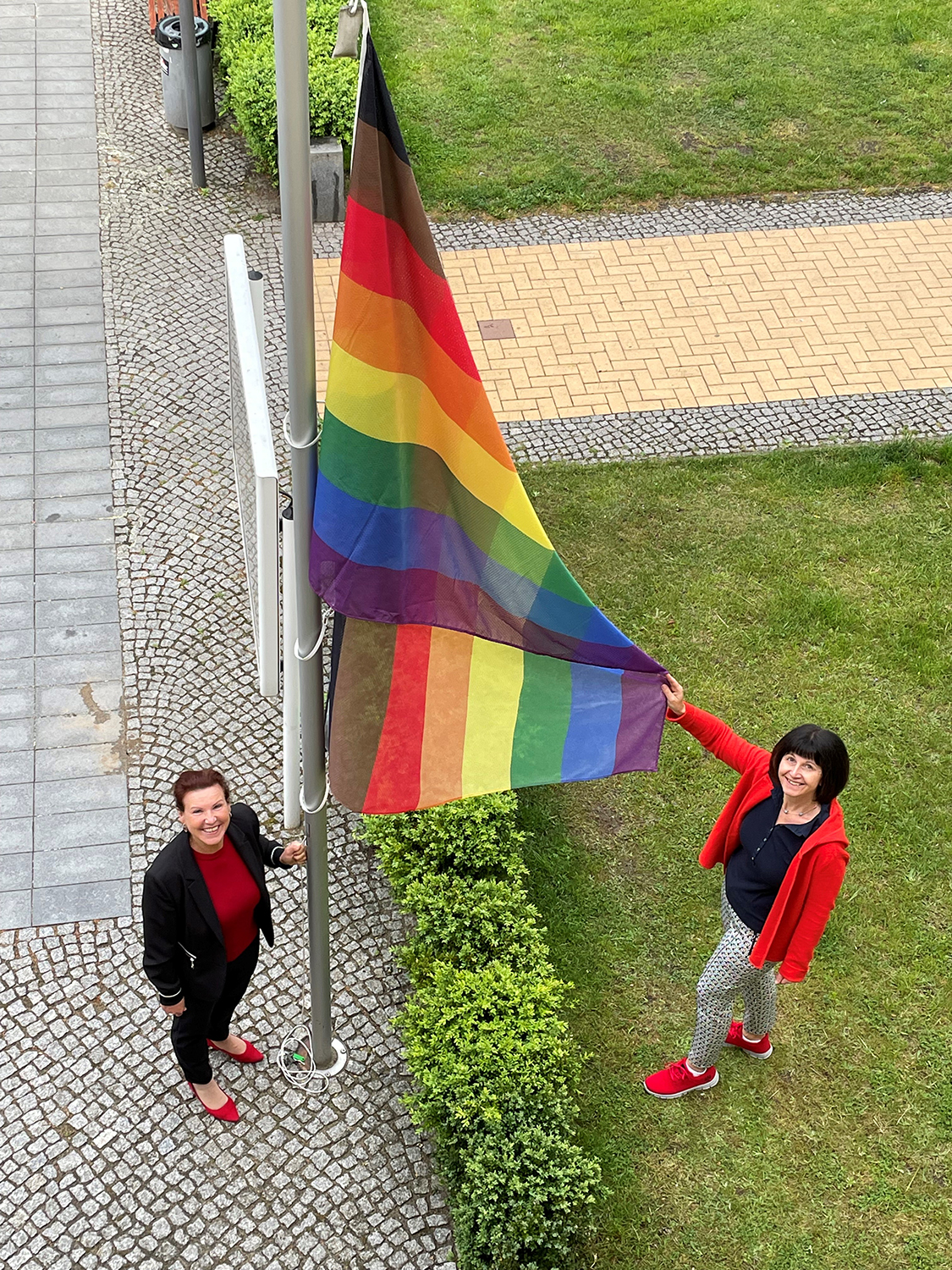 Bild vergrößern: Bürgermeisterin Ines Hübner und die ehrenamtliche Gleichstellungsbeauftragte der Stadt Velten, Kerstin Husarzewsky, hissten vor dem Rathaus die Regenbogenfahne.