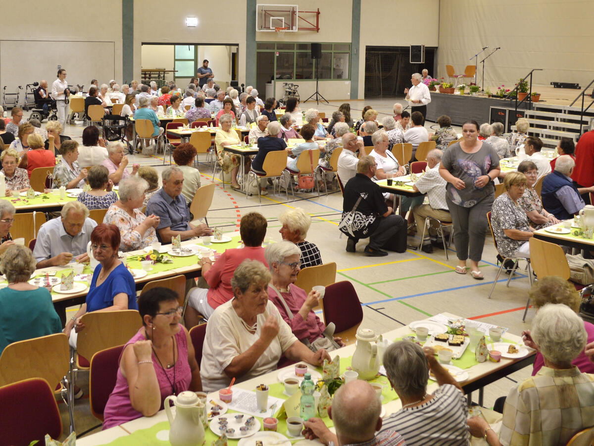 Bild vergrößern: Bei Kaffee und Kuchen sitzen die Veltener Seniorinnen und Senioren beim Seniorenfest zusammen.