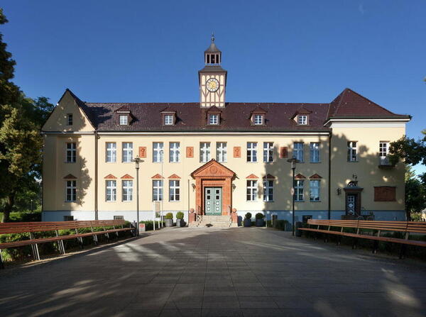 Bild vergrößern: Die Außenansicht des Rathauses Velten: Mit kleinem Glockenturm und viel Stuck und Verzierungen aus Ton.